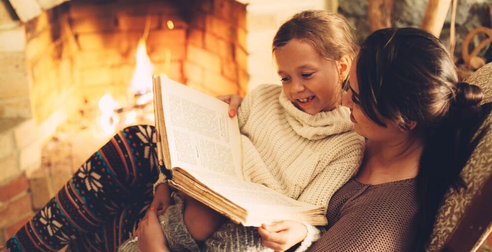 Mother and daughter reading in front of fireplace.